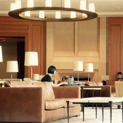 Кімната, в якій: понад стіною стоїть світлий диван, посередині кімнати лежить світлий килим, на якому стоїть стілець та лежать подушки